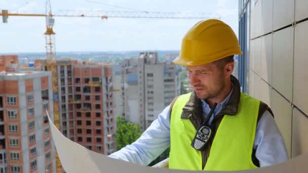 Строитель Смотрит Архитектурный План Инженер Жёлтом Шлеме Работающий Чертежом Строительной — стоковое видео