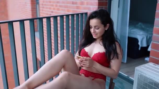 Donna Sorridente Lingerie Utilizzando Telefono Cellulare Mentre Seduto Sul Balcone — Video Stock