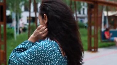 Gülümseyen genç bir kadın cep telefonu kullanıyor ve mesaj yazıyor. Akıllı telefon tutan ve dışarıda duran bir bayan. Yaşam tarzı konsepti. Gerçek zamanlı.