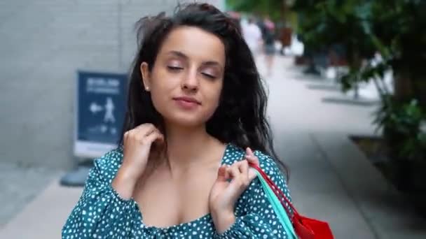 若い女性が買い物袋を持って街を歩いている 女性の買い物客が屋外を歩いて買い物袋を運ぶ リアルタイム — ストック動画
