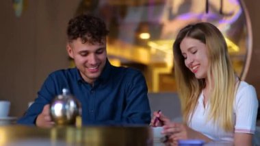 Bir kafede yemek yiyen, birbirine bakan mutlu bir çift. Gülümseyen güzel bayan erkek arkadaşını besliyor. Aşk, flört, yemek, yaşam tarzı konsepti. Gerçek zamanlı.
