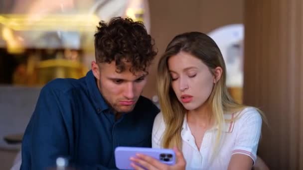 Pareja Joven Sentados Juntos Cafetería Mientras Centran Mirando Teléfono Móvil — Vídeos de Stock