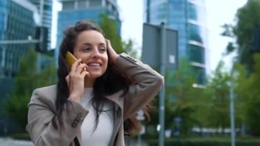 Ofis binalarıyla konuşurken akıllı telefon kullanan profesyonel bir iş kadını gibi gülümsüyorsun. Mobil uygulamalar teknolojisi. Gerçek zamanlı.