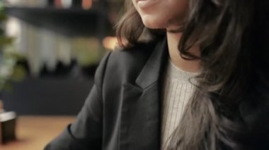 Gülümseyen kadın kafeteryada oturuyor ve dizüstü bilgisayarla çalışıyor. Mutlu iş kadını dizüstü bilgisayarda e-postaları kontrol ediyor ve klavyede hızla daktilo ediyor. Çevrimiçi ağ, konsept. Gerçek zamanlı.