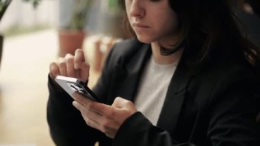 Akıllı telefon ekranında gezinen mutlu genç bayan. Kafede çalışan, cep telefonu tutan, dizüstü bilgisayar kullanan bir kadın. Çevrimiçi ağ, konsept. Gerçek zamanlı.