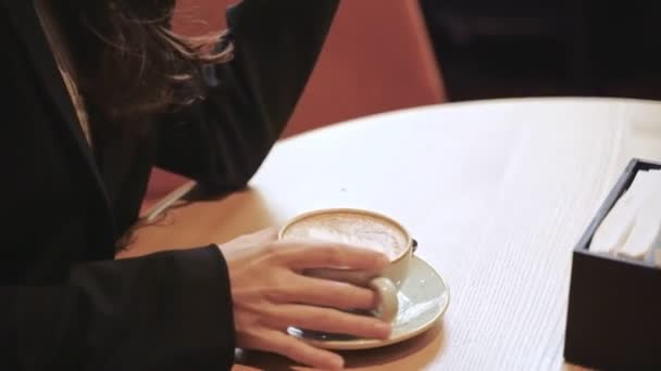 Счастливая Симпатичная Женщина Сидит Кофейне Держа Руках Смартфон Попивая Кофе — стоковое видео