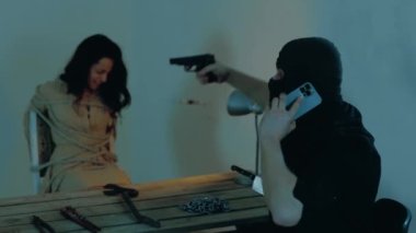Erkek kaçıran kişi cep telefonuyla konuşuyor ve terk edilmiş bir binada bir kadını tehdit ediyor. Siyah kar maskeli adam silah kullanıyor. Adam kaçırma konsepti. Yavaş çekim