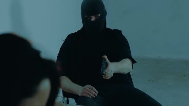 Hombre Pasamontañas Negro Sentado Una Mesa Sótano Usando Arma Amenazando — Vídeo de stock