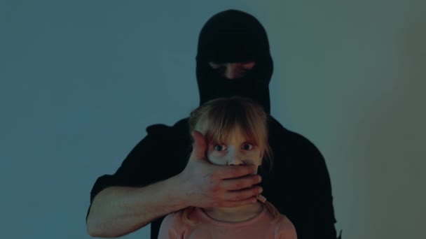 男人捂住受惊小孩的嘴穿着黑色巴拉克拉瓦的绑架者偷走了小女孩 绑架儿童的概念 慢动作 — 图库视频影像