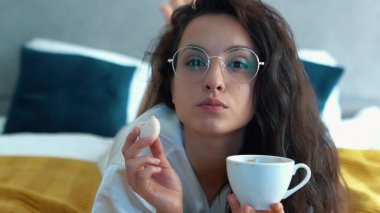 Güzel bir bayanın televizyon seyredip bir fincan kahve ya da sıcak çikolatalı kurabiye yediği bir gün. Bardaklı genç çekici kadın kurabiyeyle kahve içiyor. Boş zaman..