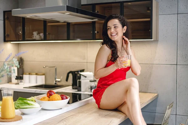 Mosolygó Csinos Hölgy Szexi Piros Peignoir Asztalon Konyhában Otthon Miközben — Stock Fotó