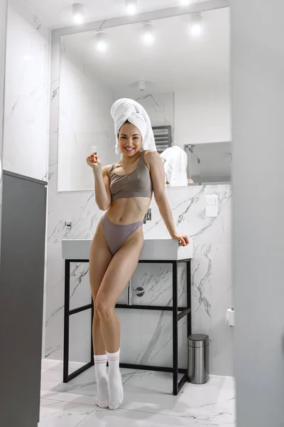 Happy lady in underwear holding ecological friendly wooden toothbrush and posing at camera. Oral hygiene treatment concept