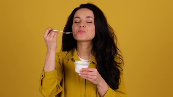 幸せな女性は 黄色の背景に隔離された瓶から新鮮な自家製ヨーグルトを食べている コピースペース 健康的な朝食のコンセプト リアルタイム — ストック動画