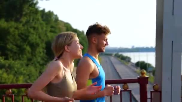 Lächelndes Junges Paar Sportkleidung Beim Morgendlichen Joggen Über Die Brücke — Stockvideo