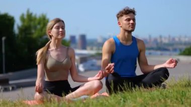 Erkek ve kadın meditasyon yaparken eğleniyorlar. Şehirde yoga yapan bir çift. Sağlıklı yaşam tarzı ve rahatlama kavramı. Gerçek zamanlı.