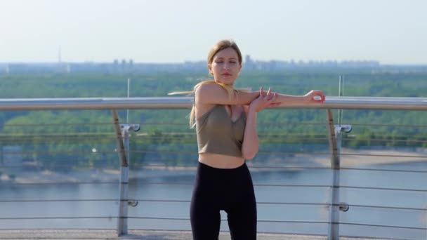 Милая Молодая Леди Делает Упражнения Растяжку Руками Перед Бежать Мосту — стоковое видео