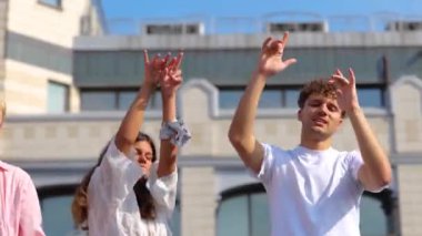 Güneşli bir yaz gününde terasta dans eden gençler çatıda eğleniyorlar. Yaşam tarzı, eğlence, açık parti konsepti. Gerçek zamanlı.