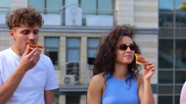 Dans ederken, pizza yerken ve ısırırken terasta dikilen iki arkadaşın gülümsemesi. Yaşam tarzı, arkadaşlık, eğlence, açık parti konsepti. Gerçek zamanlı.