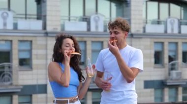 Mutlu genç adam ve bayan terasta dans ederken pizza yiyip şişe şişe şişe bira içiyorlar. Yaşam tarzı, arkadaşlık, eğlence, açık parti konsepti. Gerçek zamanlı.