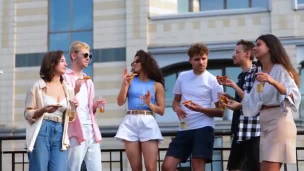 屋上の屋外でパーティーを楽しむ若者 ビールのボトルをクリックし ピザを保持 ライフスタイル 楽しさ オープンパーティーのコンセプト リアルタイム — ストック動画
