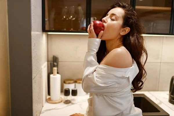 Vista Lateral Una Joven Morena Comiendo Una Manzana Roja Mientras —  Fotos de Stock