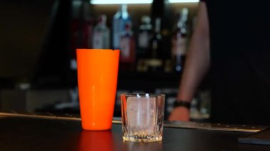 Erkek barmen bardaktan kokteyl dolduruyor. Barmen bir gece kulübünde alkollü kokteyl hazırlıyor. Kırpılmış. Yavaş çekim