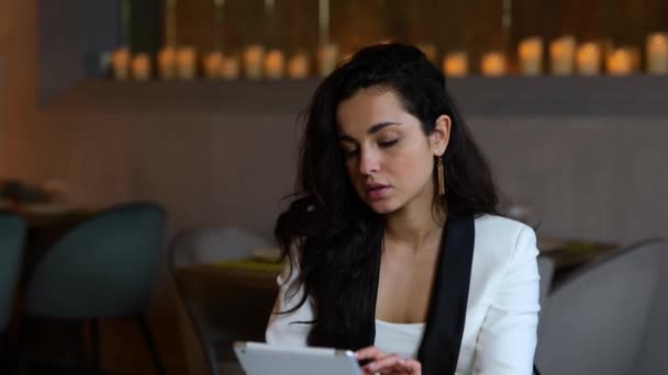 デジタルタブレットを使用しながらレストランに座っているかなり笑顔の女性は コーヒーを楽しんでいる間 画面を見ています ビジネス ライフスタイルコンセプト スローモーション — ストック動画