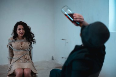 Reaver içki içiyor ve kadın bodrumda iple bağlı bir sandalyede otururken ağlıyor. Suç, adam kaçırma, şiddet kavramı