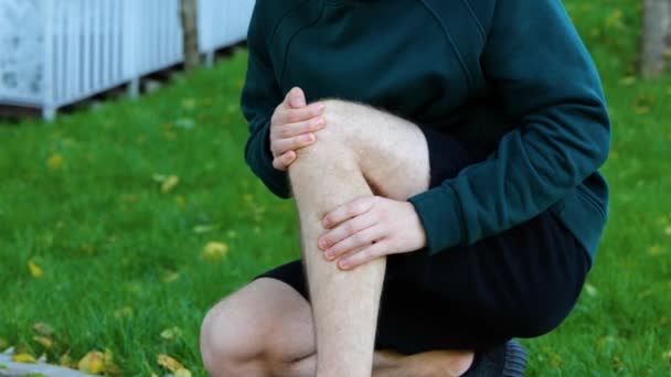 Jovem Massageando Seu Joelho Perna Músculos Parque Verde Dia Ensolarado — Vídeo de Stock