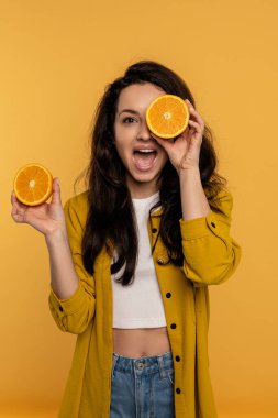 Yaramaz genç bayan, diğerini elinde tutarken, gözlerini sulu bir portakal dilimiyle kapatıyor. Sağlıklı yaşam tarzı kavramı