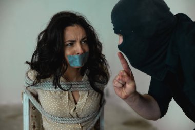 Korkmuş genç bir bayan ağzı bantla bantlanmış, sandalyeye iple bağlanmış. Erkek, kadın kurbandan sessiz olmasını istiyor. Suç, adam kaçırma, şiddet kavramı