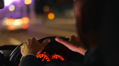 Geceleri otobanda araba sürerken direksiyonu tutan adam. Sağ el sürücüsü araba. Seyahat, gezi, gece hayatı konsepti. Gerçek zamanlı.
