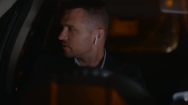 Pria Kaukasia Dengan Headphone Nirkabel Mengendarai Mobil Malam Hari Kota — Stok Video