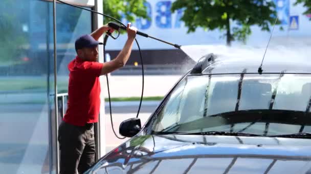 Sapkás Fiatalember Tömlőt Használ Túlnyomásos Vízzel Miközben Autóját Mossa Önkiszolgáló — Stock videók