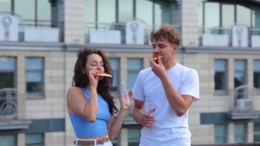 Mutlu genç adam ve bayan terasta dans ederken pizza yiyip şişe şişe şişe bira içiyorlar. Yaşam tarzı, arkadaşlık, eğlence, açık parti konsepti. Gerçek zamanlı.