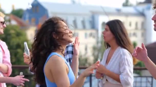 快乐的年轻女士有乐趣和她的朋友跳舞 微笑的年轻人在屋顶露台上 喝啤酒 — 图库视频影像