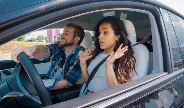 男教师把手放在方向盘上 而女教师则坐在车里 带着互动的惊讶驾驶 驾驶考试 驾驶课程 考试概念 — 图库照片