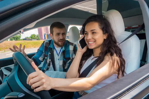 강사가 그녀에게 비명을 지르는 자동차에서 운전하고 전화로 이야기하는 행복한 운전사 — 스톡 사진