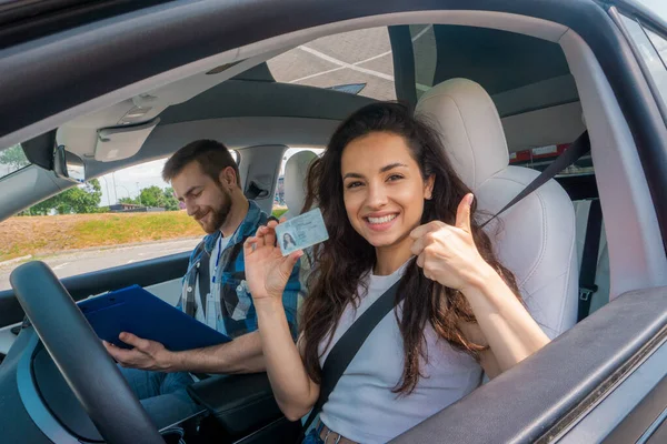 강사가 자동차에서 보드에 라이센스를 보유하고 엄지손가락을 보여주는 행복한 운전사 — 스톡 사진