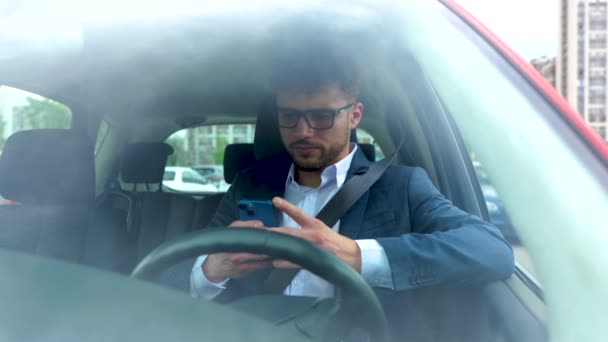 年轻的商人坐在车里 拿着智能手机 读着留言 技术和人的概念 慢动作 — 图库视频影像