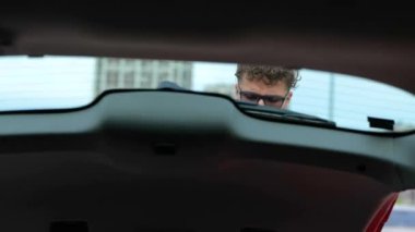 Tatile çıkmadan önce seyahat çantalarını geniş bir arabanın bagajına koyuyor. Seyahat, ulaşım, tatil, yaşam tarzı konsepti. Yavaş çekim