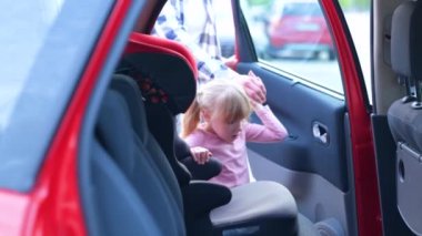 Genç adam küçük kızı arabanın arka koltuğunda emniyet kemeriyle bağlıyor. Aile, ulaşım, yolculuk, güvenlik ve ebeveynlik kavramı. Yavaş çekim