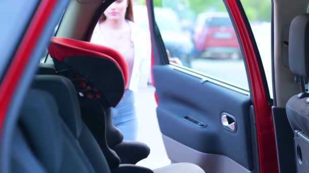 Young Mother Helping Her Daughter Sitting Car Seat While Fastening — Stock Video