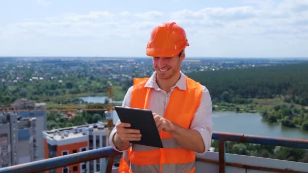 Щасливий Чоловік Будівельник Будівельній Формі Працює Даху Тримаючи Цифровий Планшет — стокове відео