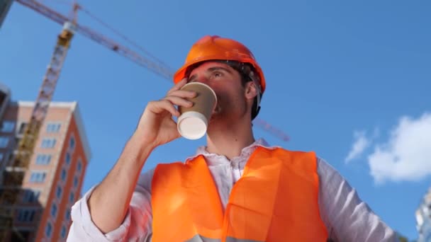 穿着硬礼帽站在建筑工地边喝热饮边笑 工业概念 慢动作 — 图库视频影像