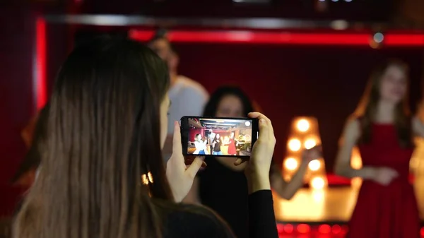 Young lady using smartphone and making video for her friends dancing in the nightclub. Lifestyle, dance, disco concept. Slow motion