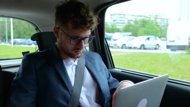 旅途中 穿着西服的男人坐在出租车后座上 一边上网一边用笔记本电脑 运输和技术概念 慢动作 — 图库视频影像