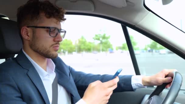 Younf Empresário Segurando Smartphone Enquanto Digita Mensagem Durante Condução Carro — Vídeo de Stock