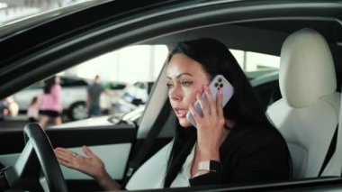 Kızgın genç bayan arabada oturuyor ve cep telefonuyla tatsız bir konuşma yapıyor. Ulaşım, teknoloji, gezi, iş konsepti. Yavaş çekim