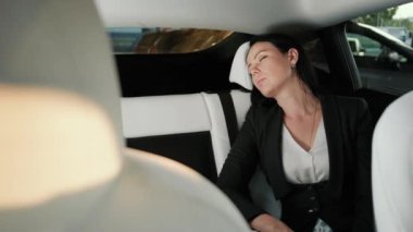 Genç bayan uyurken dinleniyor, taksinin arka koltuğunda oturuyor. Ulaşım, seyahat, iş konsepti. Yavaş çekim